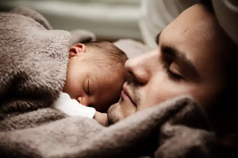 Father sleeping peacefully with his newborn baby